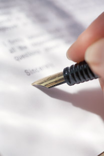 image of a hand signing a document with a pen